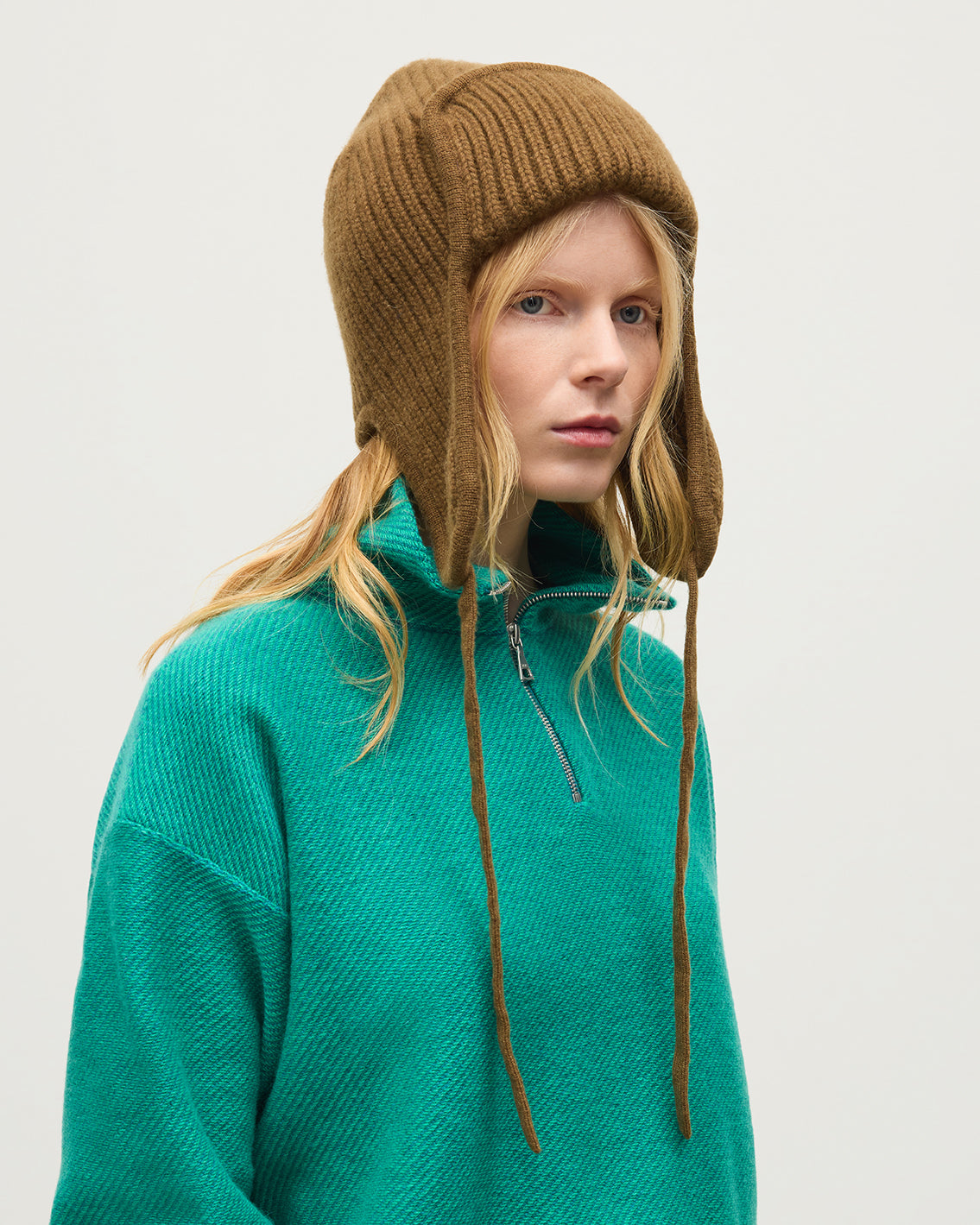 FEMALE MODEL WEARING JOHNSTONS OF ELGIN CASHMERE RIBBED DEER STALKER BEANIE GREEN 100% CASHMERE WITH REEL CASHMERE ZIP NECK IN GREEN HAT03646Q26299ONE