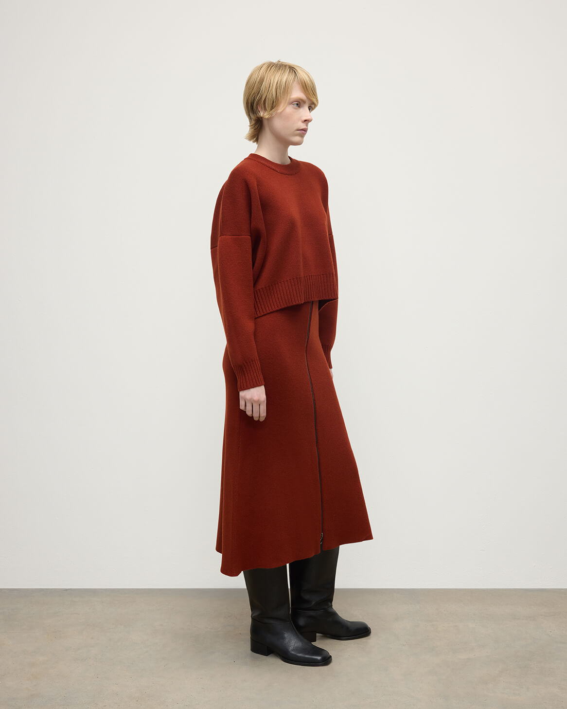 Model wears Johnstons of Elgin AW25 Women's Knitwear Oxblood A-Line Milano Red Cashmere Skirt Side View KAA05600SG4463