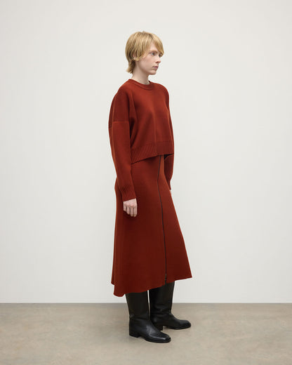 Model wears Johnstons of Elgin AW25 Women's Knitwear Oxblood A-Line Milano Red Cashmere Skirt Side View KAA05600SG4463