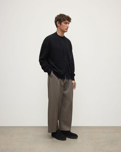 Model wearing Johnstons of Elgin AW25 Men's Knitwear Black & Iron Plaited Texture Black Cashmere Cardigan Side View KAA05579Q25387