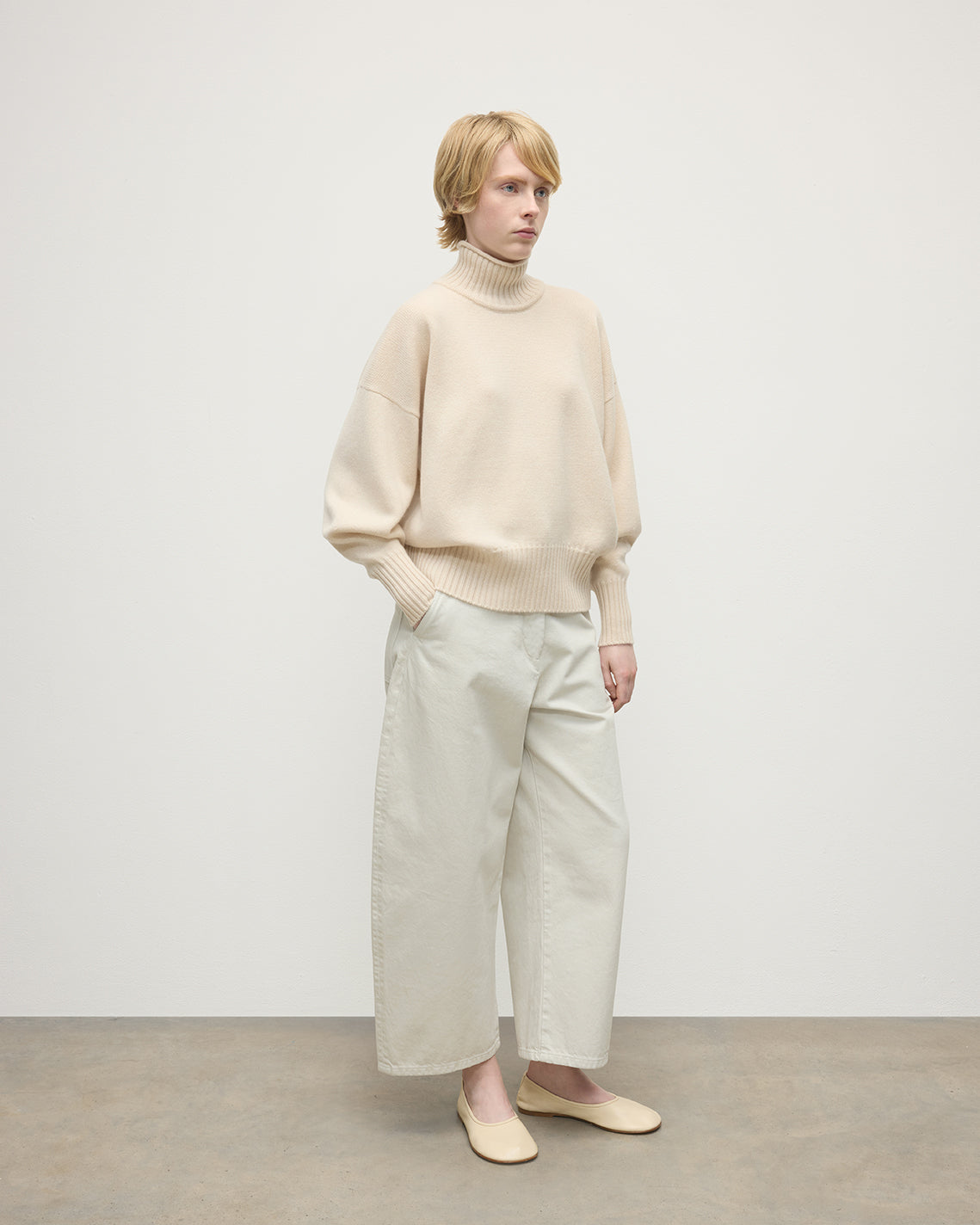 Model wearing Johnstons of Elgin AW25 Women's Knitwear Champagne High Neck Cream Cashmere Jumper Side View  KAA05585SA0502
