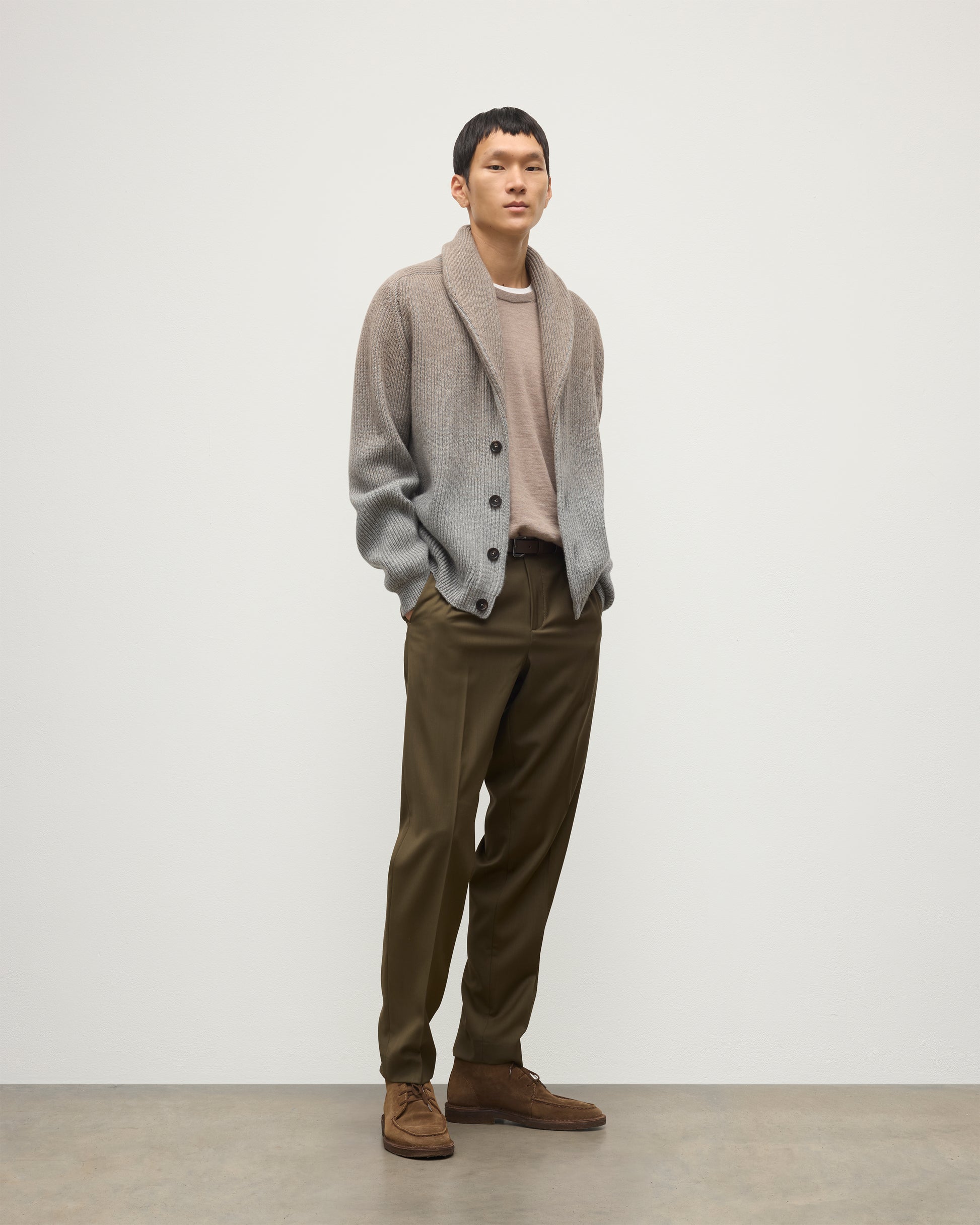 MALE MODEL WEARING JOHNSTONS OF ELGIN PIONEER SHAWL CARDIGAN GREY 100% CASHMERE WITH OLIVE GREEN CHINOS, OVER A SUPERFINE CASHMERE LIGHT BROWN SWEATER AND WHITE T-SHIRT KAA05750Q25948