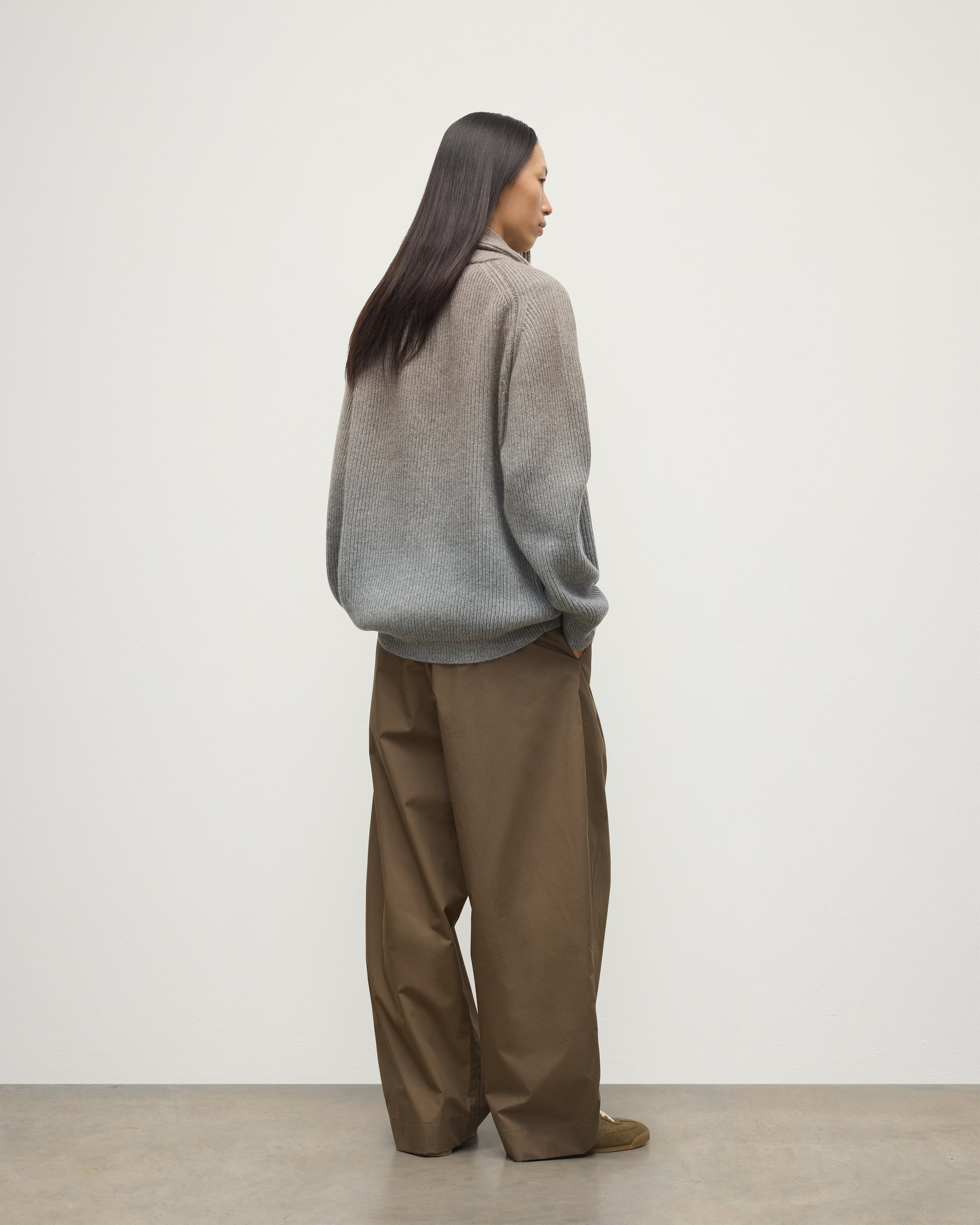 BACK OF FEMALE MODEL WEARING JOHNSTONS OF ELGIN PIONEER SHAWL CARDIGAN GREY 100% CASHMERE WITH BROWN WIDE LEG CHINOS, WHITE T-SHIRT & TRAINERS UAA05750Q25948