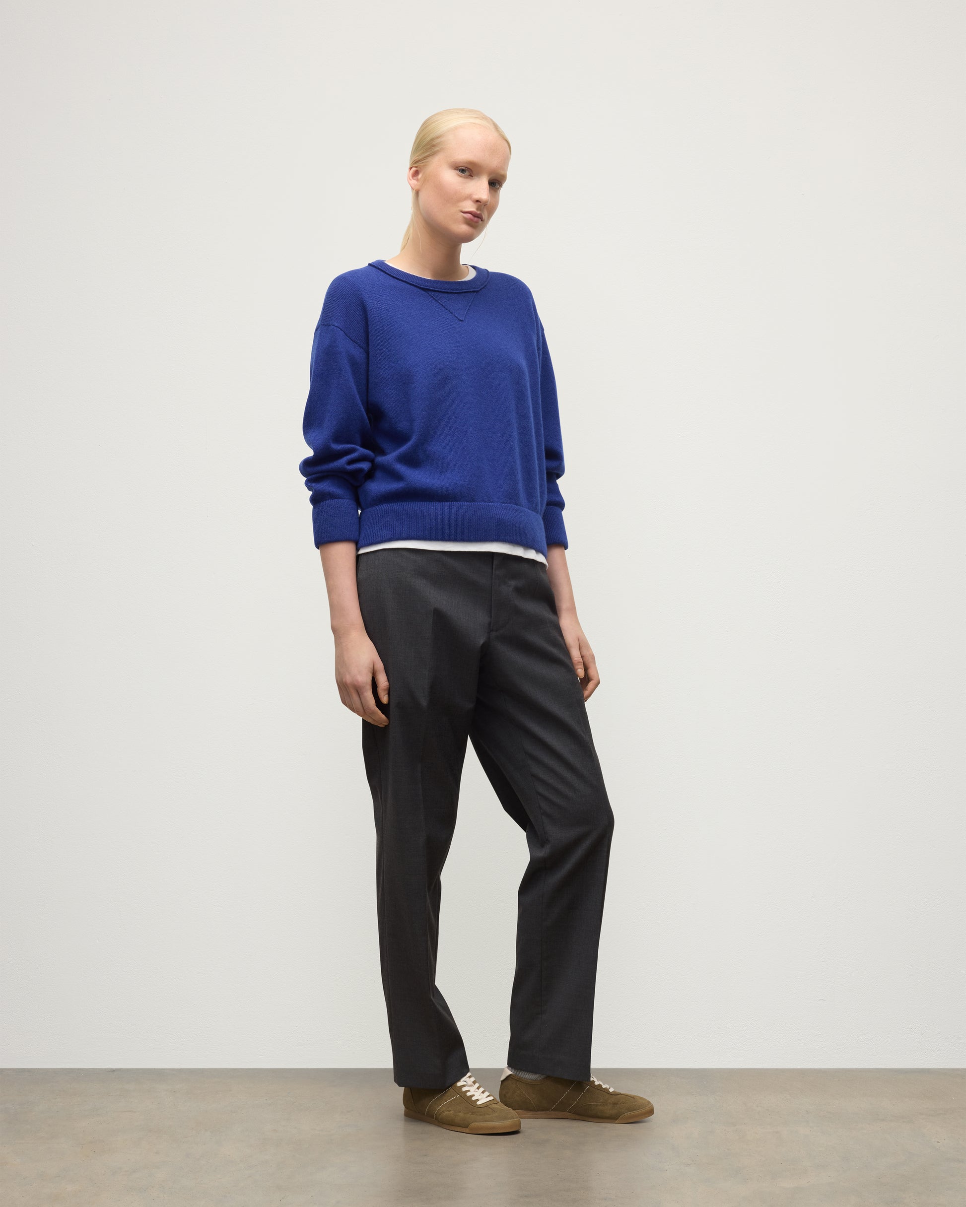 MODEL WEARING JOHNSTONS OF ELGIN WOMENS STELLA SWEATSHIRT BLUE 100% CASHMERE OVER A WHITE T_SHIRT, WITH DARK GREY TROUSERS KAA05770SD5326