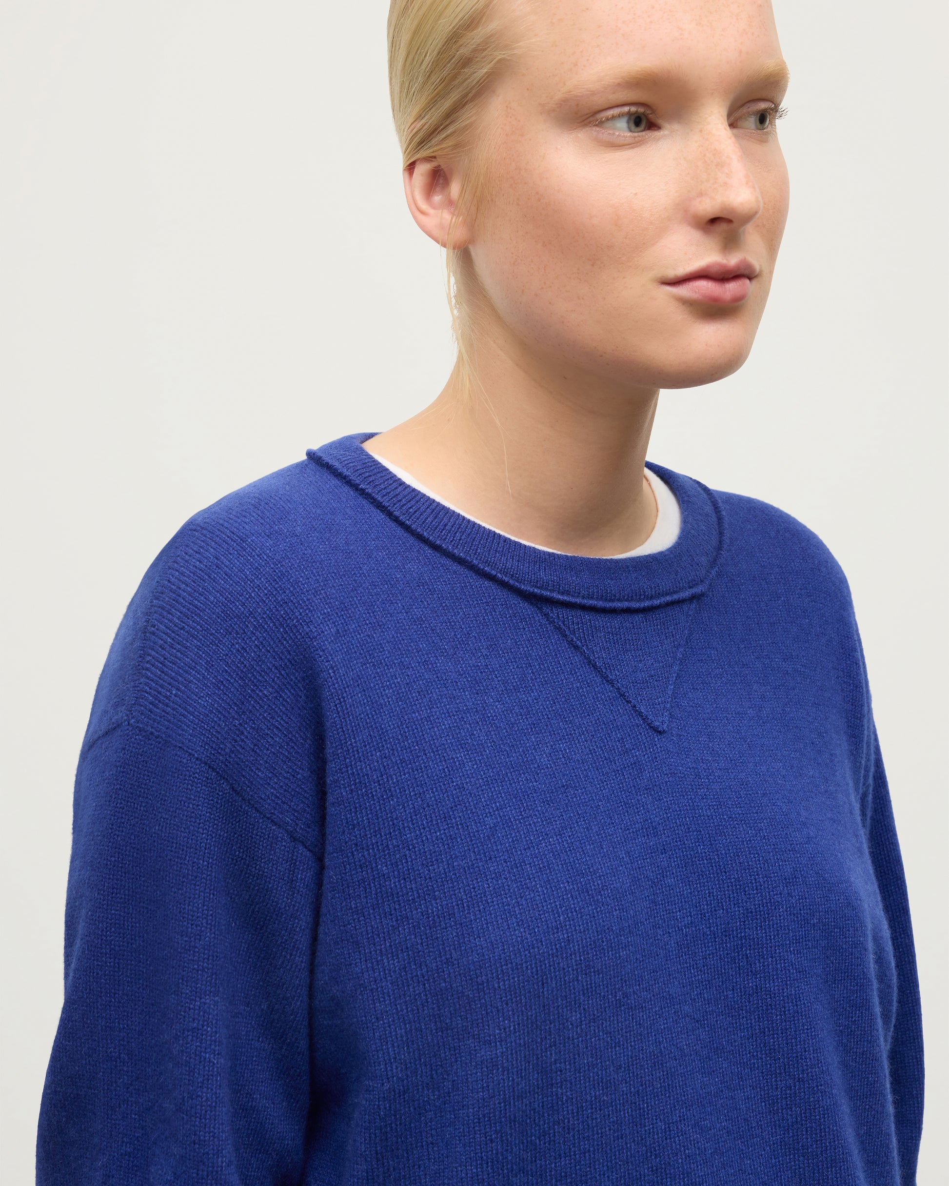 MODEL WEARING JOHNSTONS OF ELGIN WOMENS STELLA SWEATSHIRT BLUE 100% CASHMERE OVER A WHITE T_SHIRT KAA05770SD5326