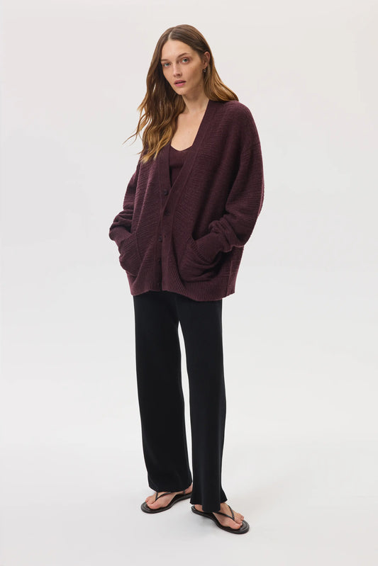 Female model wearing Johnstons of Elgin SS25 Unisex Knitwear Rosewood Textured Cashmere Cardigan with superfine cashmere vest, black trousers against a white background KAC05415SB7089