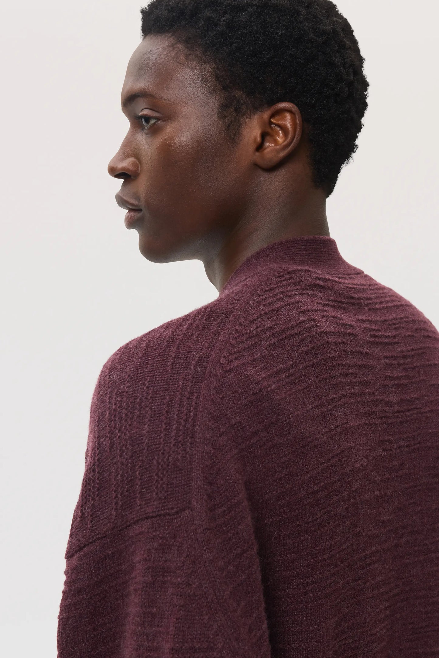 Male model wearing Johnstons of Elgin SS25 Unisex Knitwear Rosewood Textured Cashmere Cardigan on a white background KAC05415SB7089