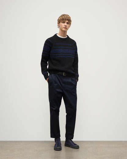 MODEL WEARS JOHNSTONS OF ELGIN  MENS SUMMIT CREW SWEATER BLACK & BLUE 100% CASHMERE OVER A WHITE T-SHIRT WITH NAVY TROUSERS KAC05752Q25949