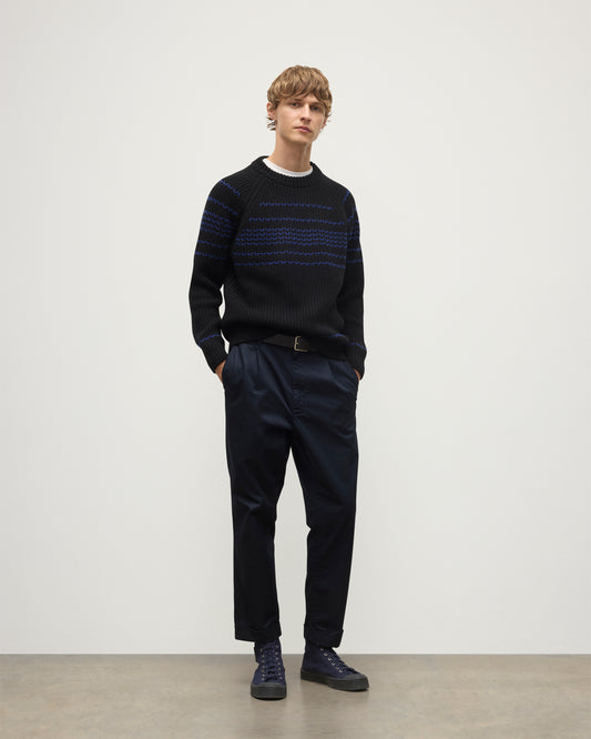 MODEL WEARS JOHNSTONS OF ELGIN  MENS SUMMIT CREW SWEATER BLACK & BLUE 100% CASHMERE OVER A WHITE T-SHIRT WITH NAVY TROUSERS KAC05752Q25949