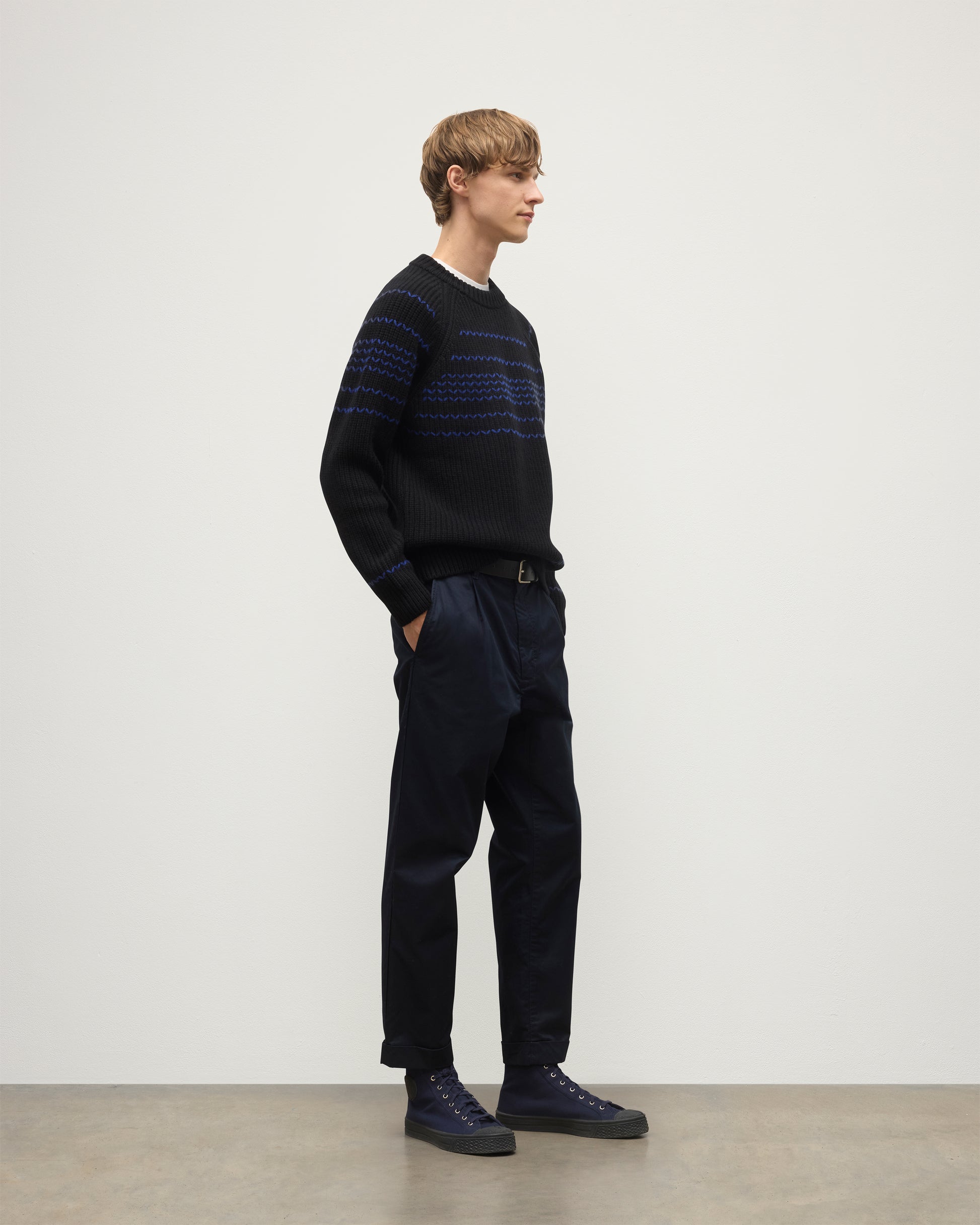 MODEL WEARS JOHNSTONS OF ELGIN  MENS SUMMIT CREW SWEATER BLACK & BLUE 100% CASHMERE OVER A WHITE T-SHIRT WITH NAVY TROUSERS KAC05752Q25949
