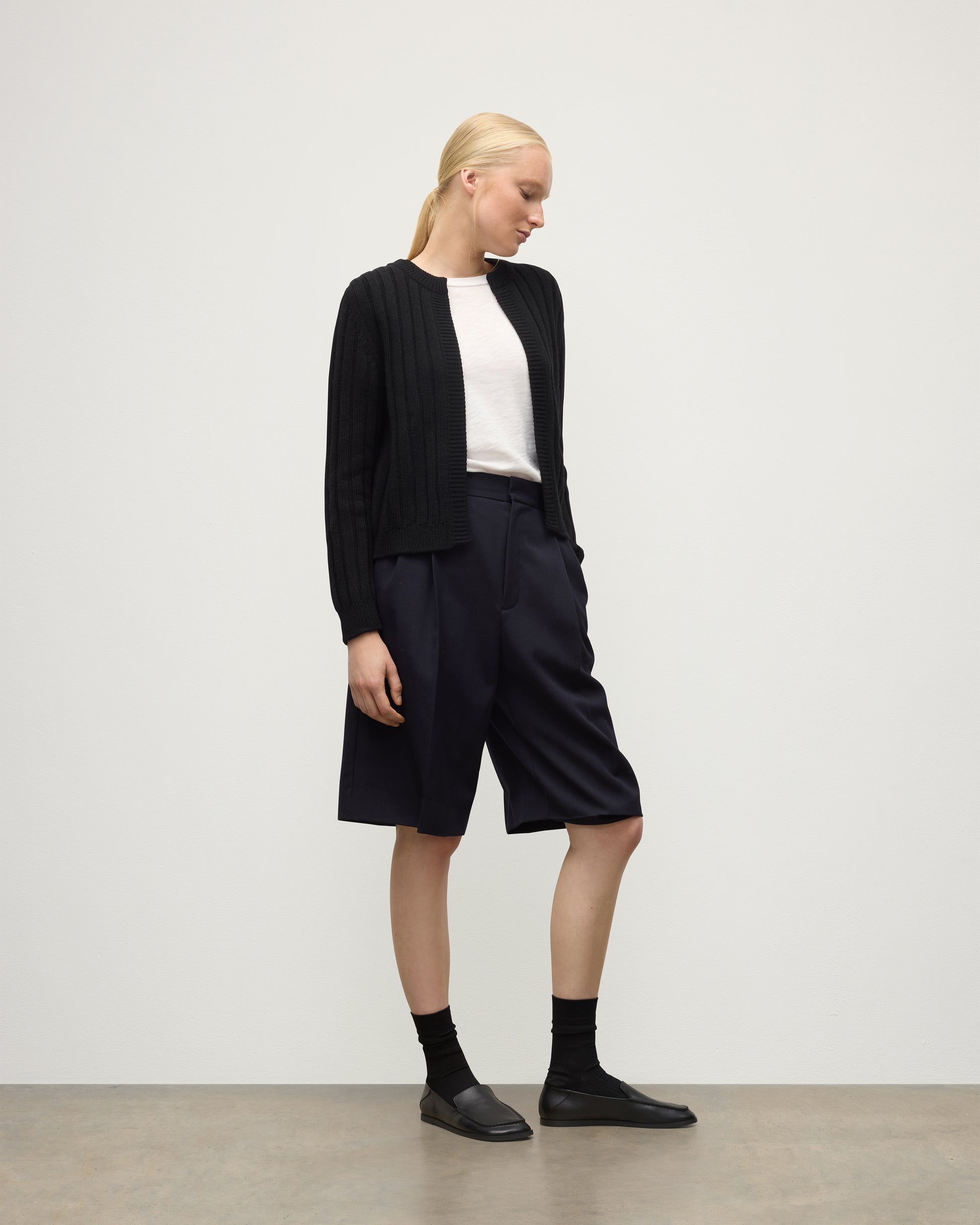 MODEL WEAR JOHNSTONS OF ELGIN WOMENS LECHT CREW CARDIGAN BLACK 100% CASHMERE OVER A WHITE T-SHIRT & LONG NAVY SHORRTS KAC05790SA7210