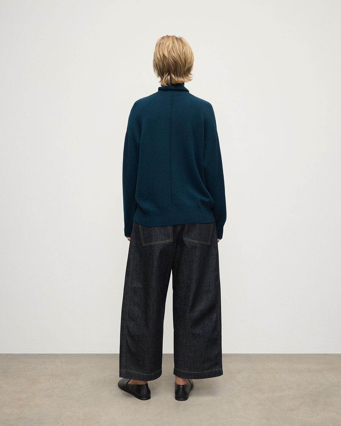 Model wears Johnstons of Elgin AW25 Women's Knitwear Bottle Green Gauzy Cashmere Green Roll Neck Jumper Back View KAI05324SC7341