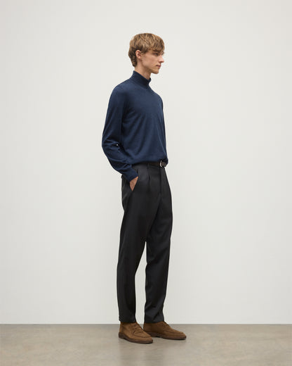 MODEL WEARS JOHNSTONS OF ELGIN MENS SUPERFINE FIN ROLL COLLAR NAVY 100% SUPERFINE CASHMERE  WITH GREY TROUSERS AND BROWN BELT KAI05333HD7350