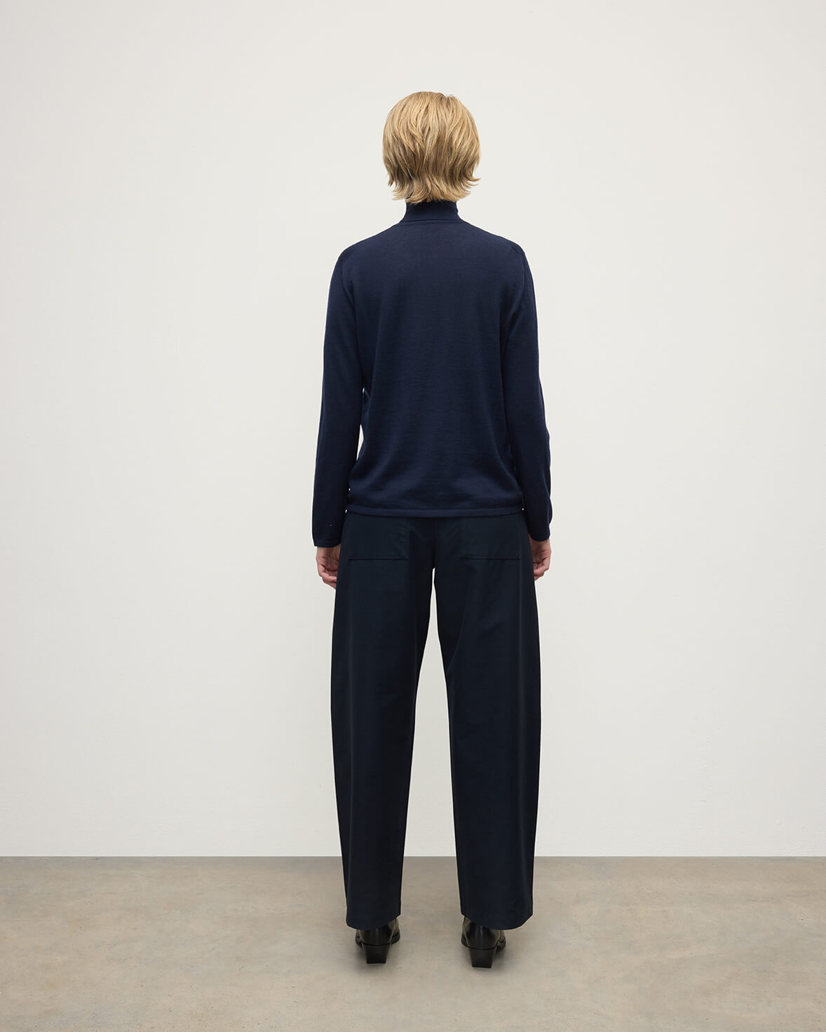 Model wears Johnstons of Elgin AW25 Women's Knitwear Dark Navy Superfine Cashmere Navy Roll Neck Jumper Back View KAI05607SD7600