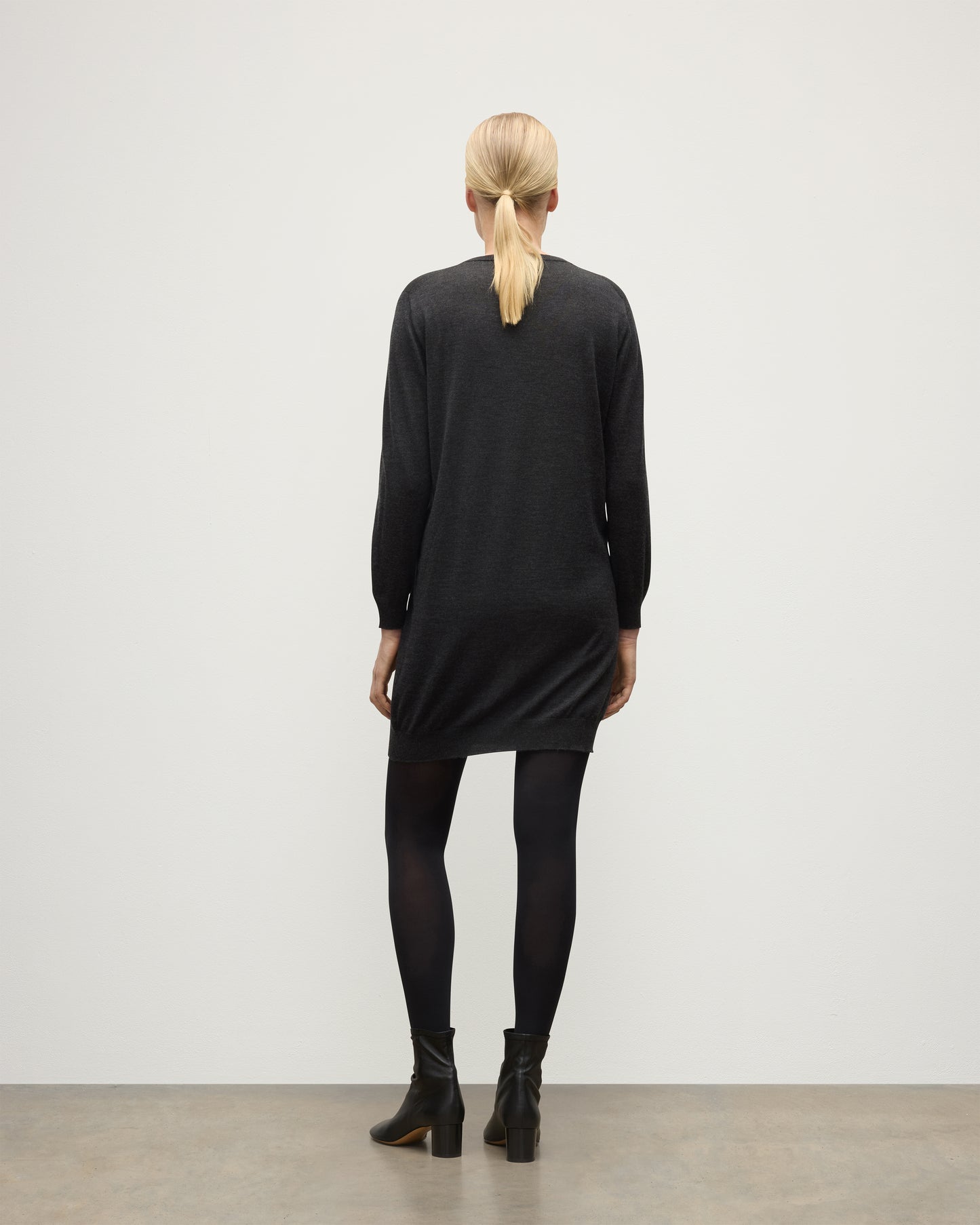 MODEL WEARING JOHNSTONS OF ELGIN WOMENS ELISE VEE SWEATER GREY 100% SUPERFINE CASHMERE WITH BLACK TIGHTS AND BOOTS KAI05715HA7218
