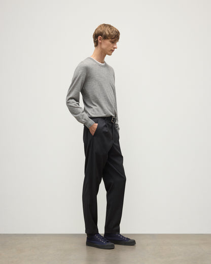 MODEL WEARS JOHNSTONS OF ELGIN MENS FIN SUPERFINE CREW GREY 100% SUPERFINE CASHMERE  OVER A WHITE T-SHIRT WITH GREY TROUSERS KAI05717HA4253