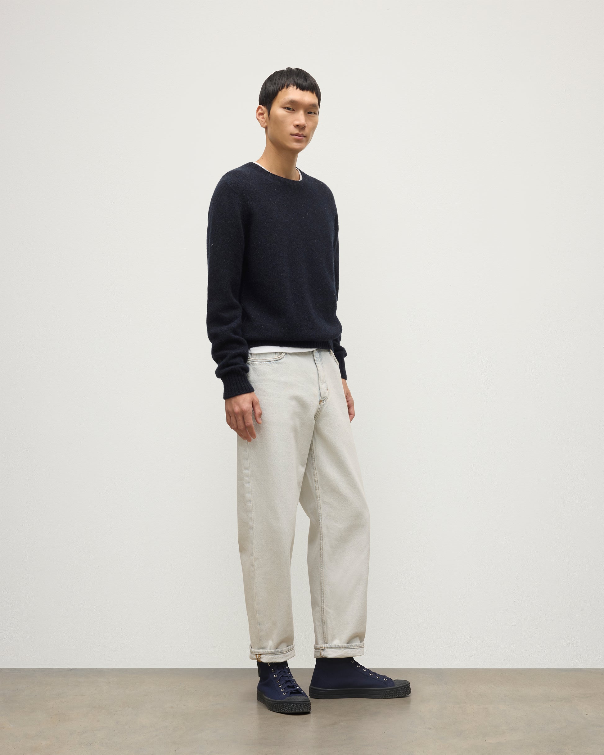 MODEL WEARS JOHNSTONS OF ELGIN  MENS TIREE CREW SWEATER BLUE 100% DONEGAL CASHMERE WITH WHITE JEANS KAI05755HD7348