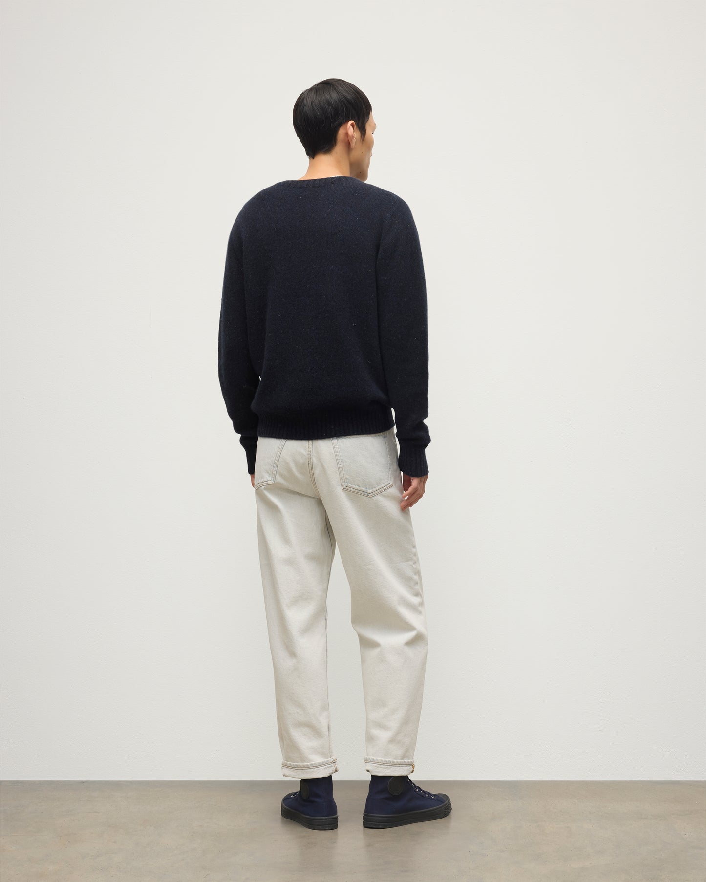 MODEL WEARS JOHNSTONS OF ELGIN  MENS TIREE CREW SWEATER BLUE 100% DONEGAL CASHMERE WITH WHITE JEANS KAI05755HD7348