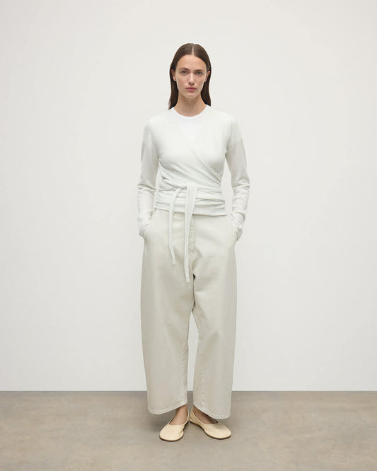 Model wearing Johnstons of Elgin AW25 Women's Knitwear White Featherlight Cashmere Ballet Wrap with white trousers on a light background KAP05408HA0346