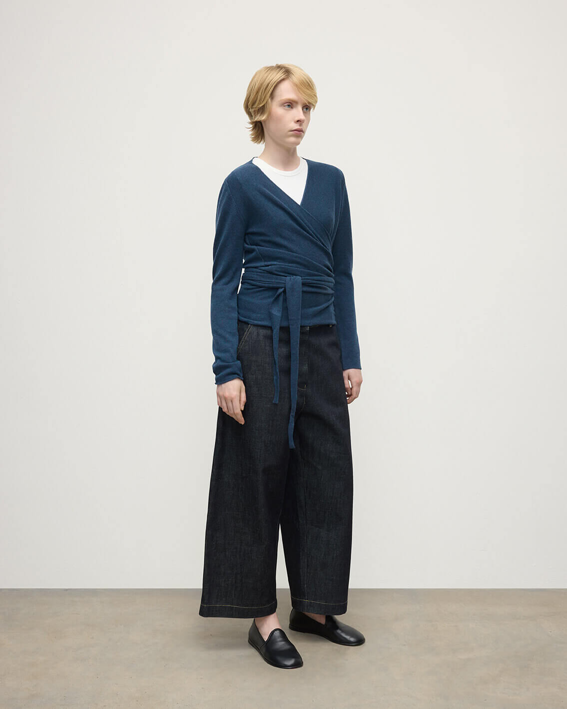 Model wears Johnstons of Elgin AW25 Women's Knitwear Heather Navy Ballet Wrap Navy Cashmere Cardigan Side View KAP05408HD7321