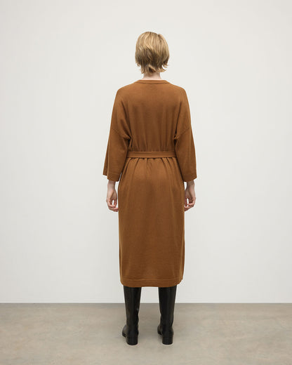 Model wears Johnstons of Elgin AW25 Women's Knitwear Dark Camel Tie-Waist Cashmere Camel Jumper Dress Back View  KAP05490SB4620