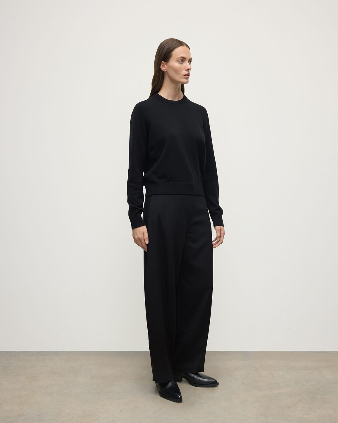 Model wears Johnstons of Elgin AW25 Women's Knitwear Black Classic Cashmere Black Round Neck Jumper Side View KAP05572SA7210