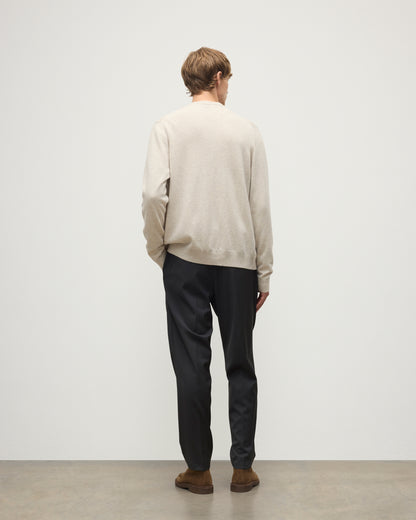 MODEL WEARS JOHNSTONS OF ELGIN MENS RORY VEE NECK CLASSIC CARDIGAN NATURAL 100% CASHMERE OVER A MATCHING V NECK SWEATER WITH GREY TROIUSERS KAP05576HA0402