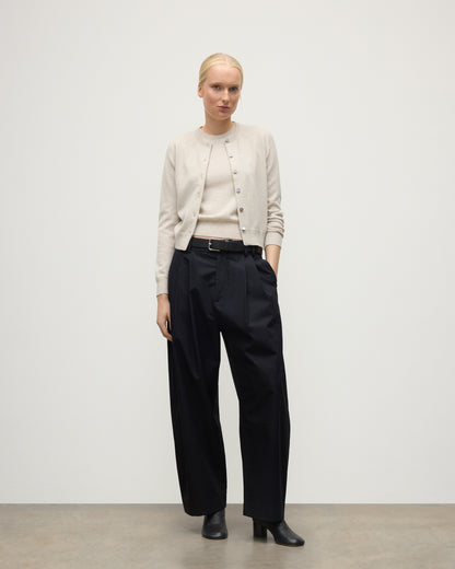 MODEL WEARING JOHNSTONS OF ELGIN WOMENS IRIS CLASSIC CREW CARDIGAN NATURAL 100% CASHMERE WITH NAVY TROUSERS AND BLACK BOOTS KAP05704HA0402