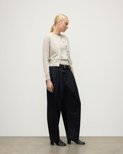MODEL WEARING JOHNSTONS OF ELGIN WOMENS IRIS CLASSIC CREW CARDIGAN NATURAL 100% CASHMERE WITH NAVY TROUSERS AND BLACK BOOTS KAP05704HA0402