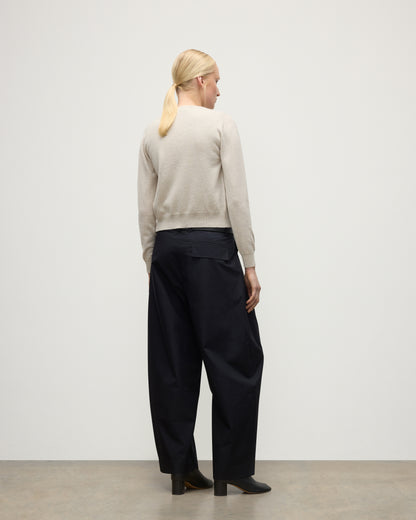 MODEL WEARING JOHNSTONS OF ELGIN WOMENS IRIS CLASSIC CREW CARDIGAN NATURAL 100% CASHMERE WITH NAVY TROUSERS AND BLACK BOOTS KAP05704HA0402