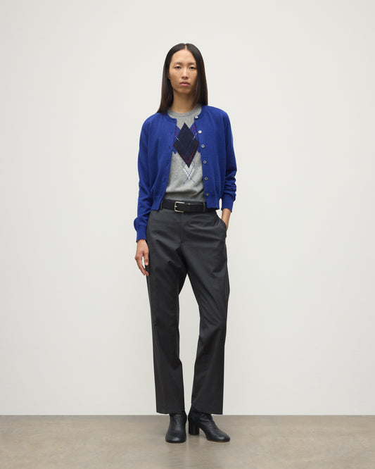 MODEL WEARING JOHNSTONS OF ELGIN WOMENS IRIS CLASSIC CREW CARDIGAN BLUE 100% CASHMERE OVER LE JABOT CASHMERE TANK WITH GREY TROUSERS AND BLACK BOOTS KAP05704SD5326