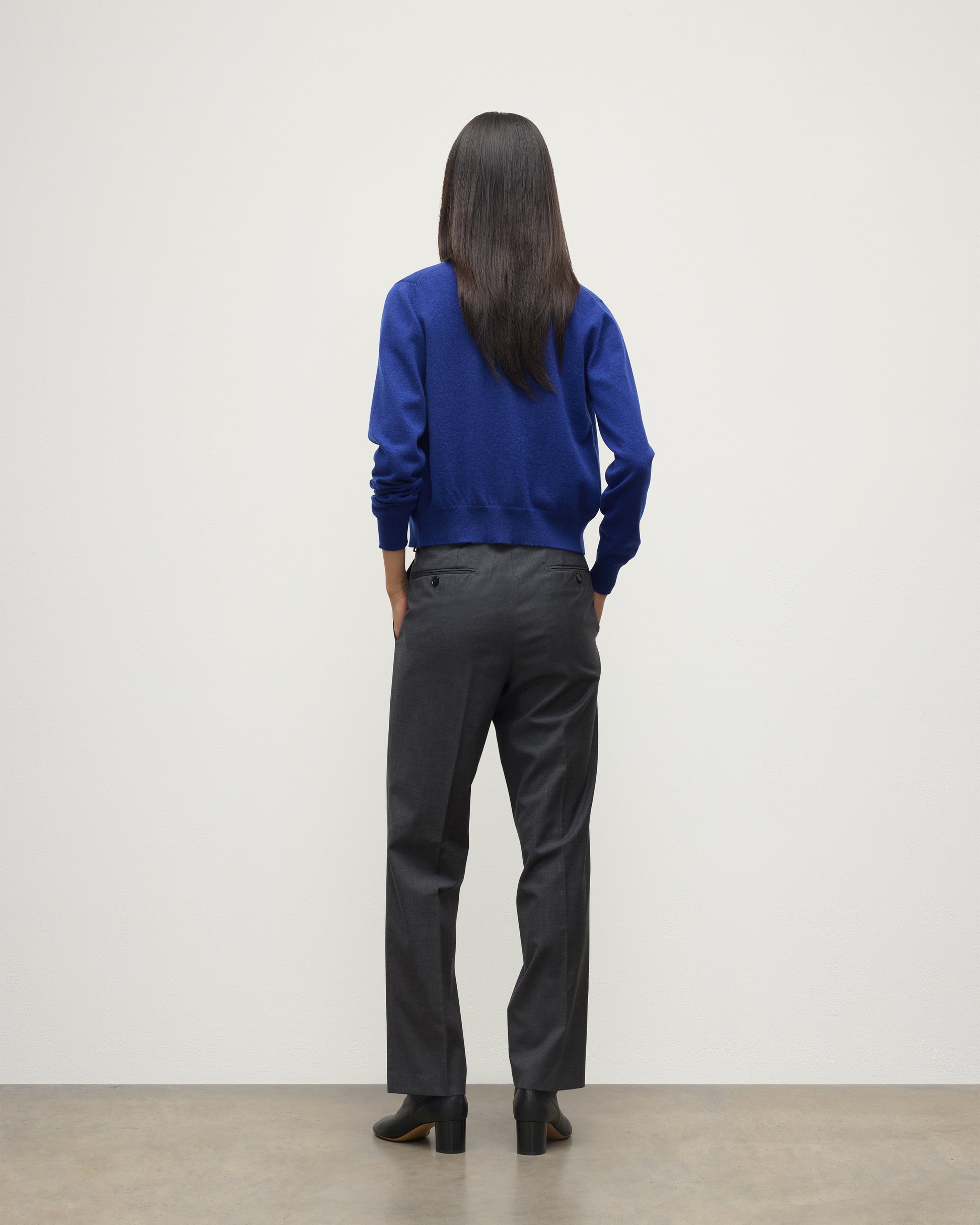 MODEL WEARING JOHNSTONS OF ELGIN WOMENS IRIS CLASSIC CREW CARDIGAN BLUE 100% CASHMERE OVER LE JABOT CASHMERE TANK WITH GREY TROUSERS AND BLACK BOOTS KAP05704SD5326