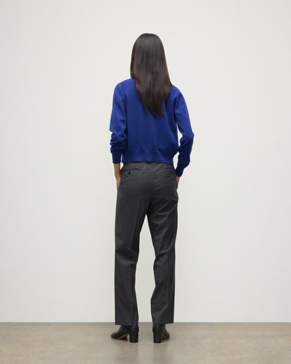 MODEL WEARING JOHNSTONS OF ELGIN WOMENS IRIS CLASSIC CREW CARDIGAN BLUE 100% CASHMERE OVER LE JABOT CASHMERE TANK WITH GREY TROUSERS AND BLACK BOOTS KAP05704SD5326