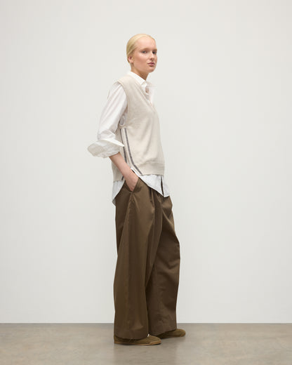 MODEL WEARS JOHNSTONS OF ELGIN WOMENS TILDA SLEEVELESS VEE NATURAL 100% CASHMERE OVER A WHITE SHIRT, WITH BROWN TROUSERS KAP05767Q25969