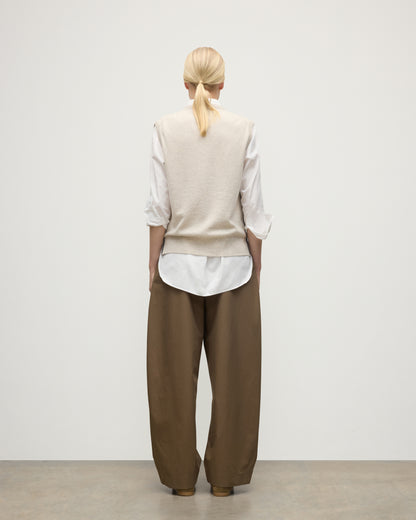 MODEL WEARS JOHNSTONS OF ELGIN WOMENS TILDA SLEEVELESS VEE NATURAL 100% CASHMERE OVER A WHITE SHIRT, WITH BROWN TROUSERS KAP05767Q25969