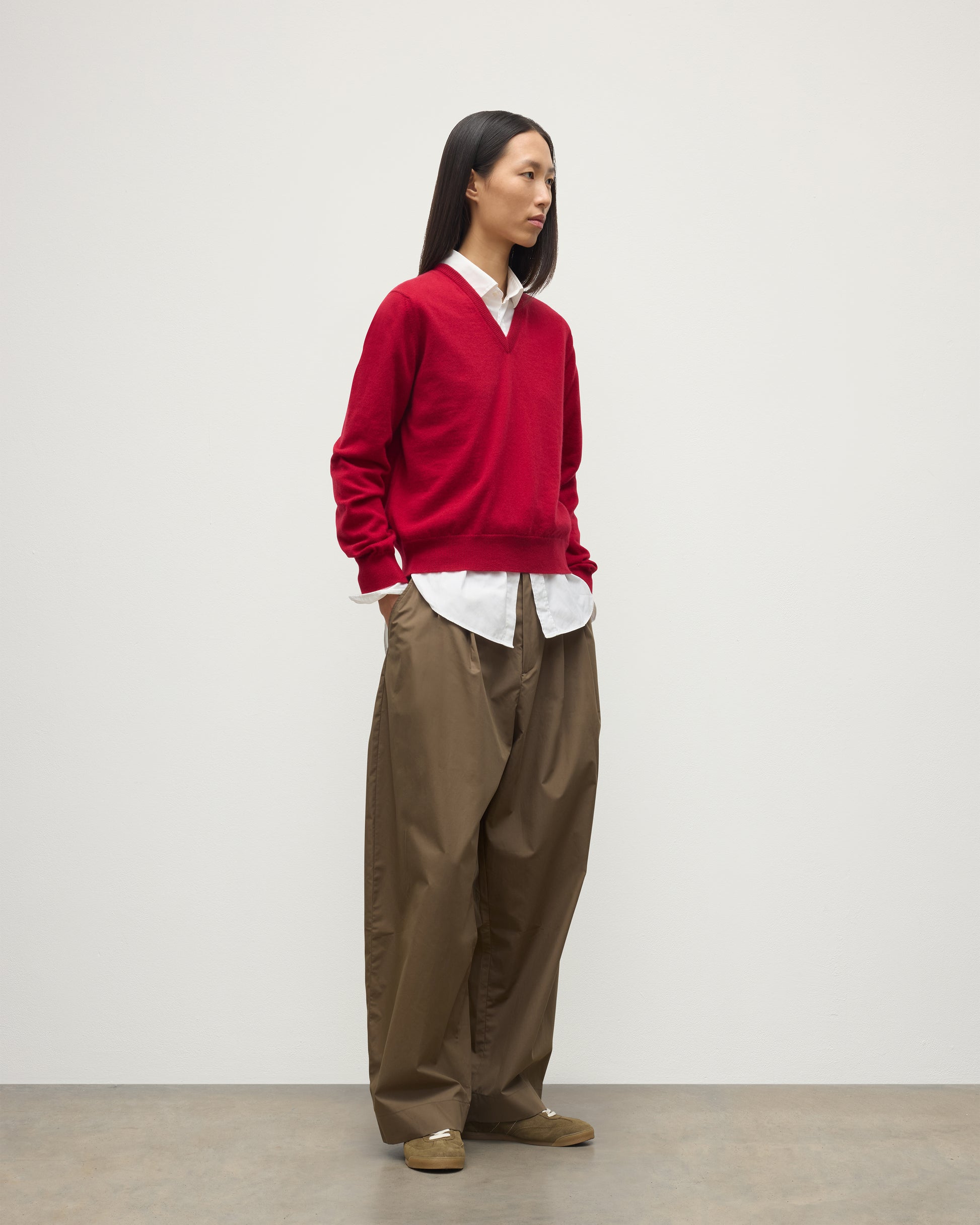 MODEL WEARING JOHNSTONS OF ELGIN WOMENS LUNAN CLASSIC VEE SWEATER RED 100% CASHMERE OVER WHITE SHIRT WITH BROWN TROUSERS KAP05807SE5325