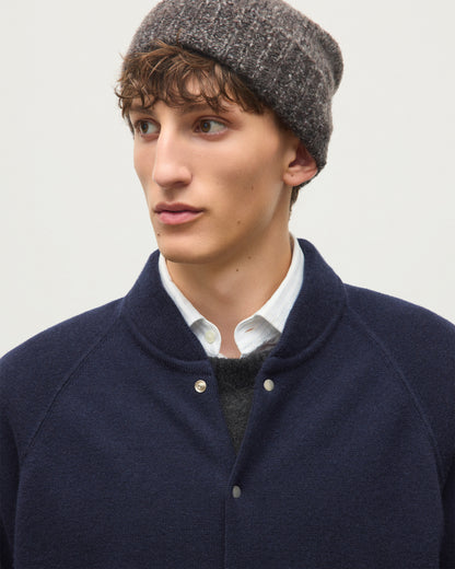 A man wearing a dark navy blue knit button-up cardigan over a white collared shirt and dark gray sweater, paired with a gray knit beanie, photographed against a light gray background. JOHNSTONS OF ELGIN KEPPIE BOMBER JACKET CASHMERE MILANO STITCH BOMBER JACKET - 2 PLY NAVY 100% CASHMERE KAP06008SD7666