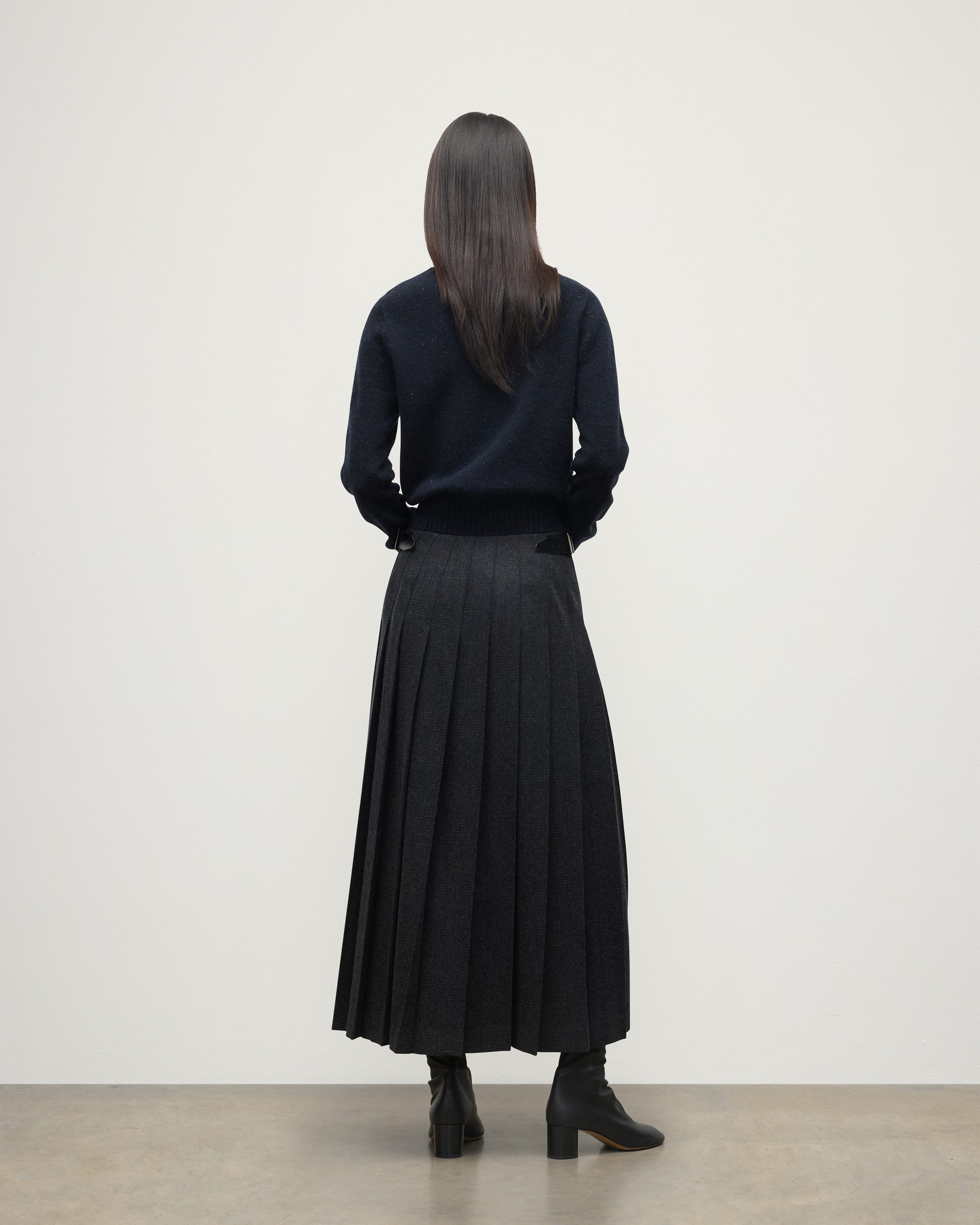 MODEL WEARING LE KILT X JOHNSTONS OF ELGIN LONG CHARCOAL KILT IN WOOL AND CASHMERE, WORN WITH DARK GREY CASHMERE SWEATER WITH BLACK BOOTS TB000844RU7750