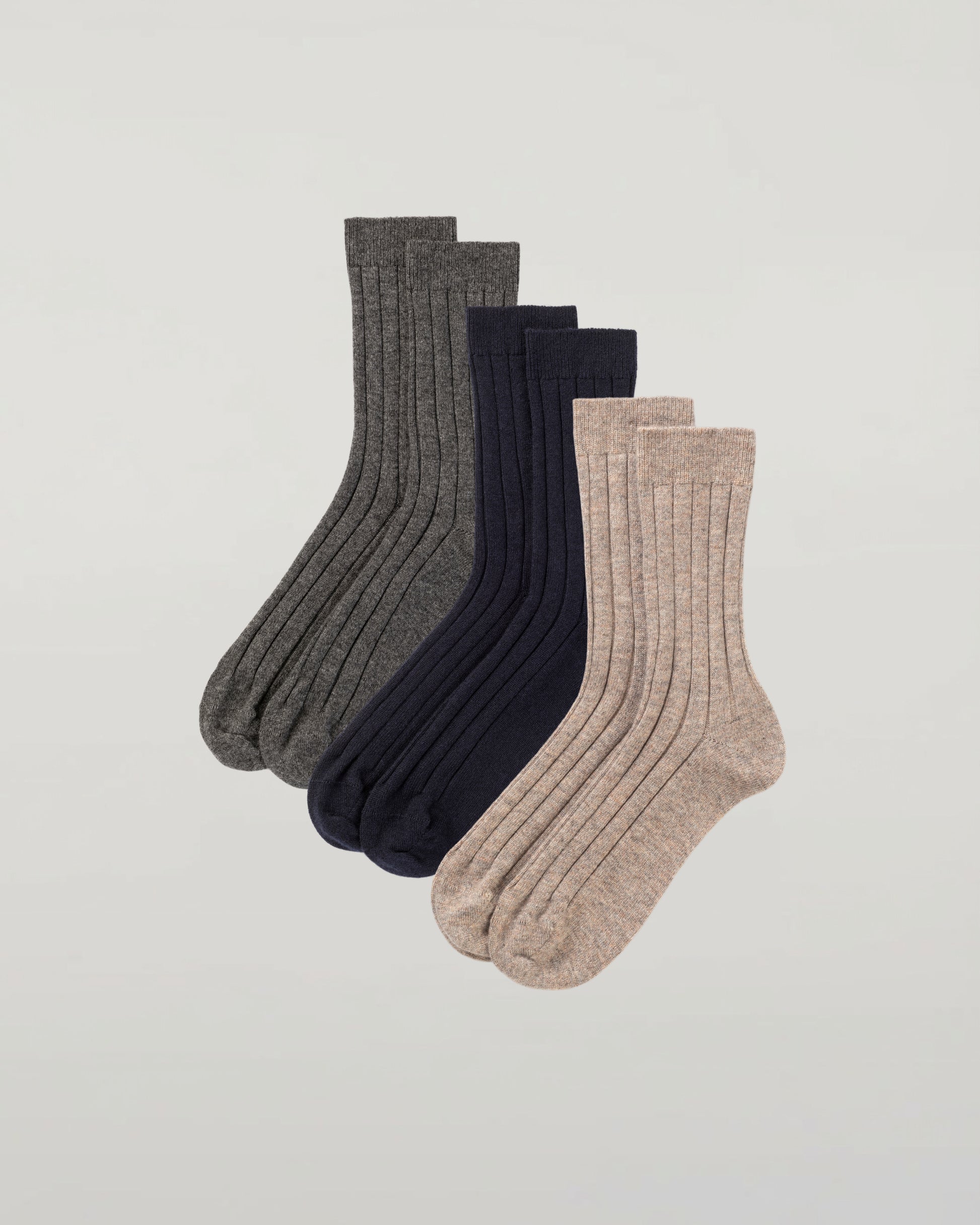 Johnstons of Elgin set of three pairs of cashmere socks in grey, navy, and beige on a light grey background 2025GIFTSET2