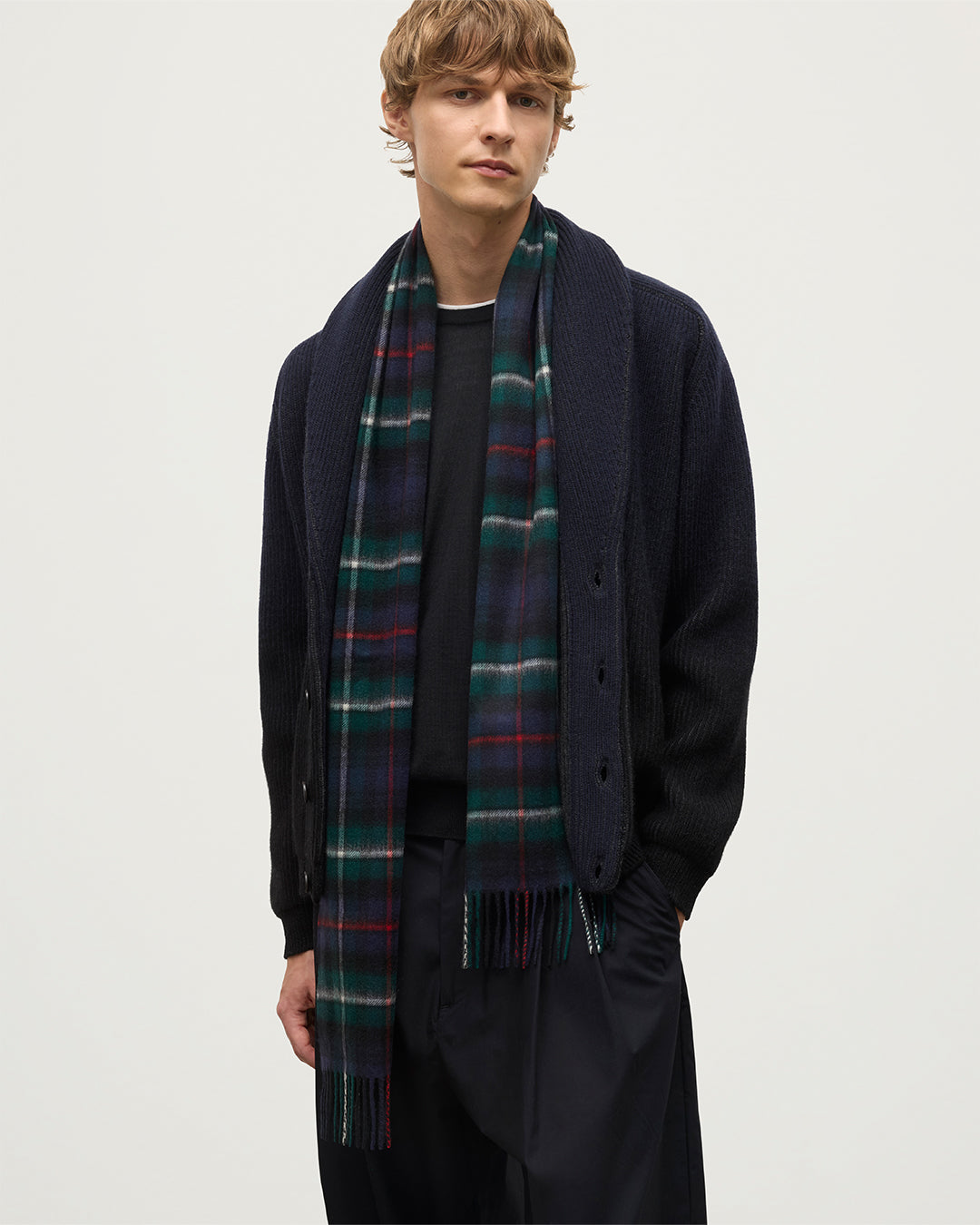 MALE MODEL WEARING JOHNSTONS OF ELGIN PIONEER SHAWL CARDIGAN NAVY & BLACK 100% CASHMERE WITH BLACK SUPERFINE CASHMERE SWEATER IWTH MACKENZIE TARTAN SCARF KAA05750Q25947