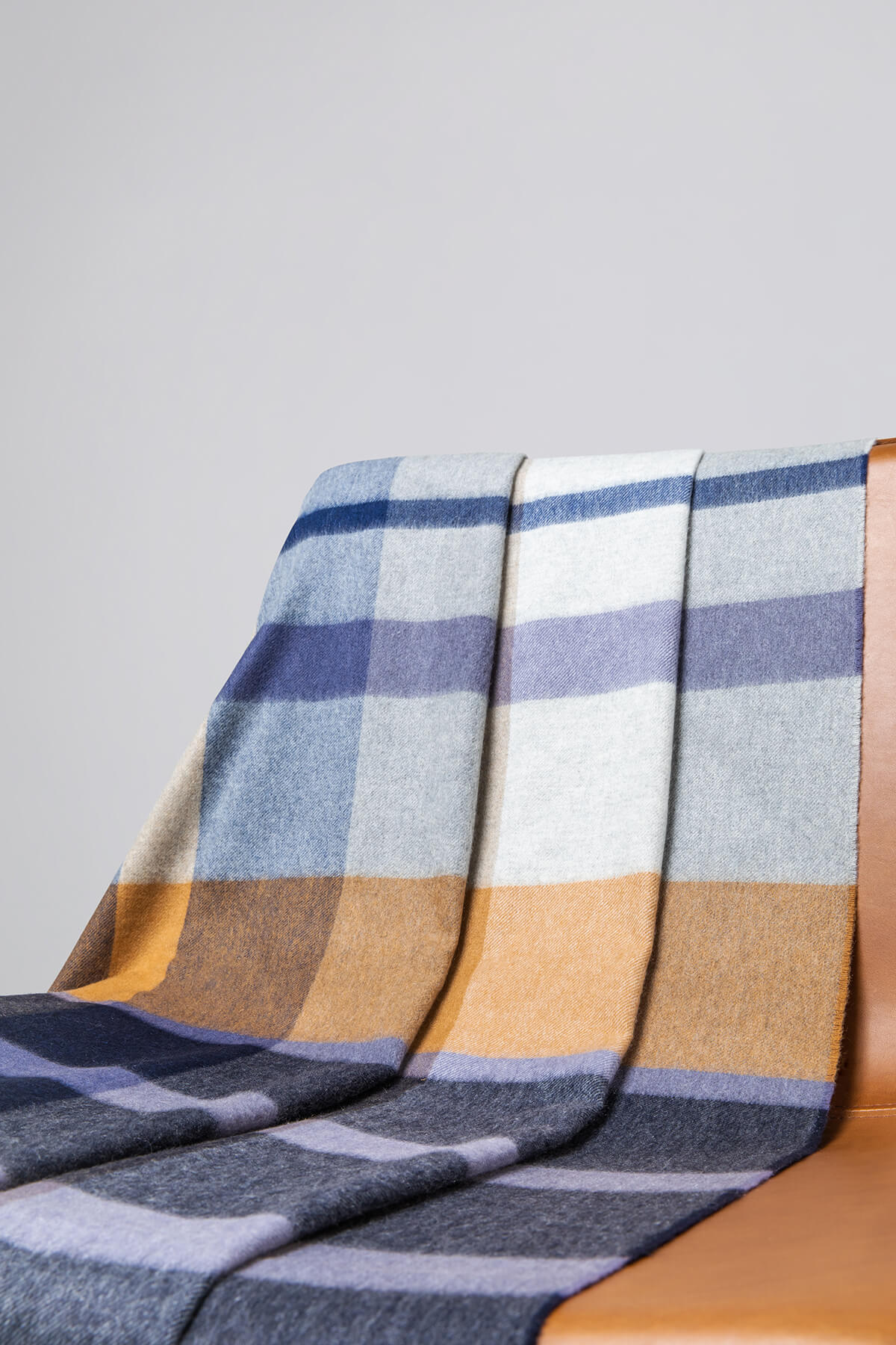 Johnstons of Elgin’s House Check Cashmere Throw on brown chair on a grey background WA000055RU7060ONE