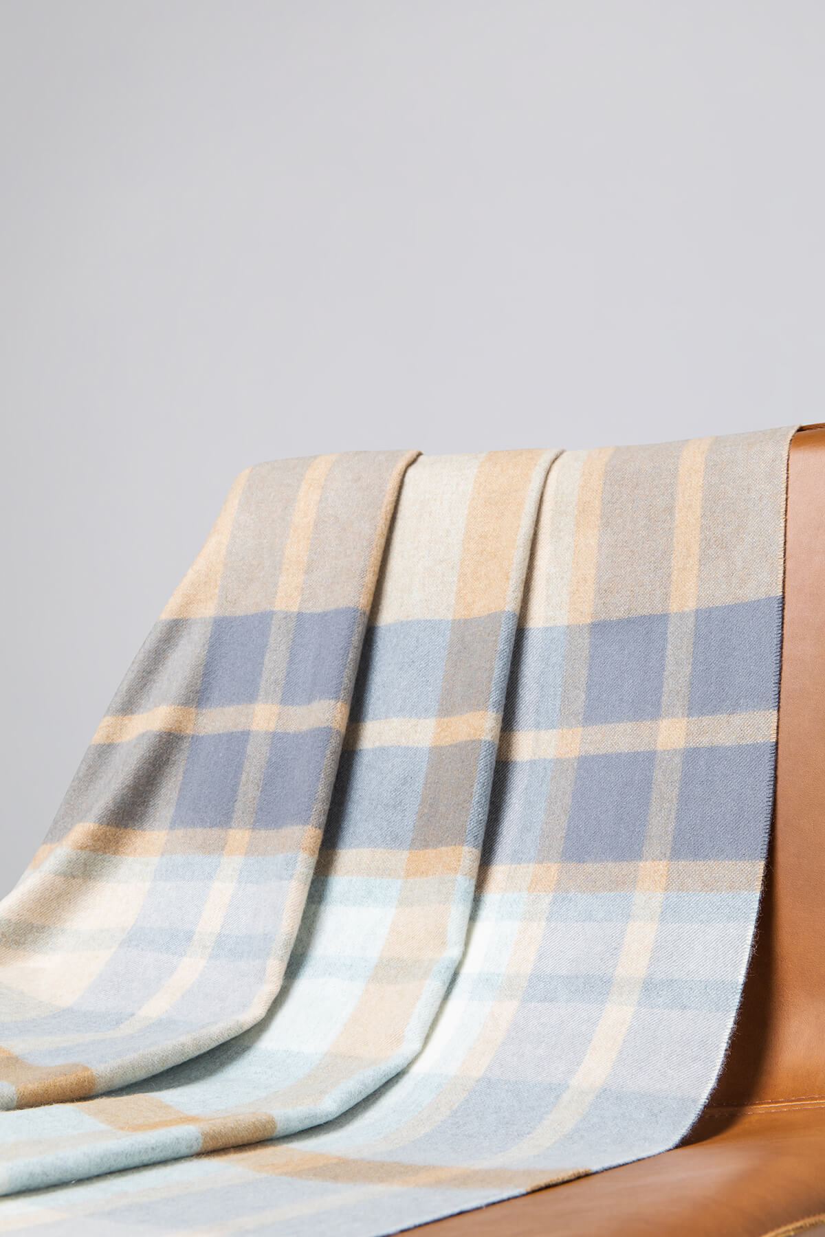 Johnstons of Elgin’s Lochcarron Hunting Weathered Check Cashmere Throw on brown chair on a grey background WA000055RU7271ONE